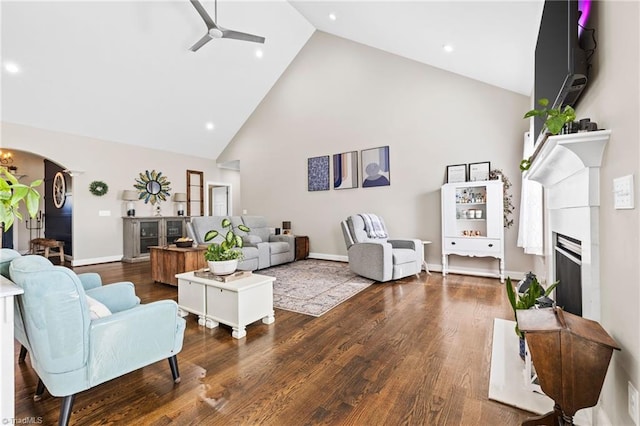 living area featuring arched walkways, wood finished floors, high vaulted ceiling, and ceiling fan