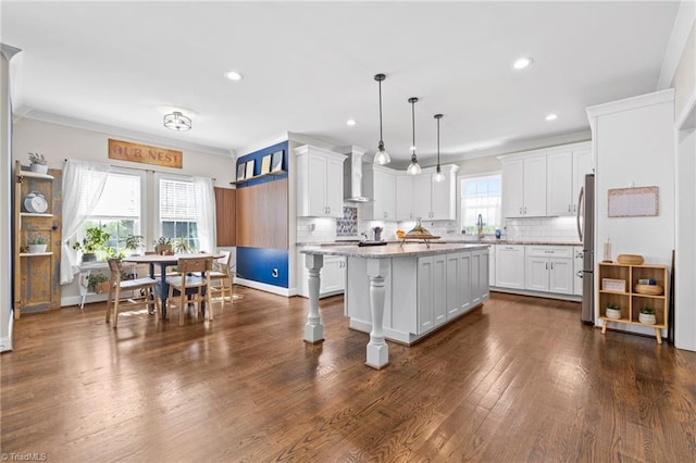 kitchen with tasteful backsplash, wall chimney exhaust hood, a center island, and white cabinetry