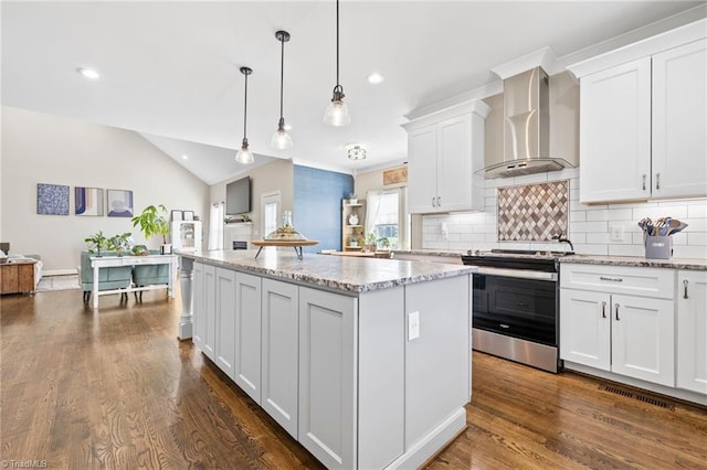 kitchen featuring a center island, vaulted ceiling, decorative backsplash, stainless steel range with electric stovetop, and wall chimney range hood