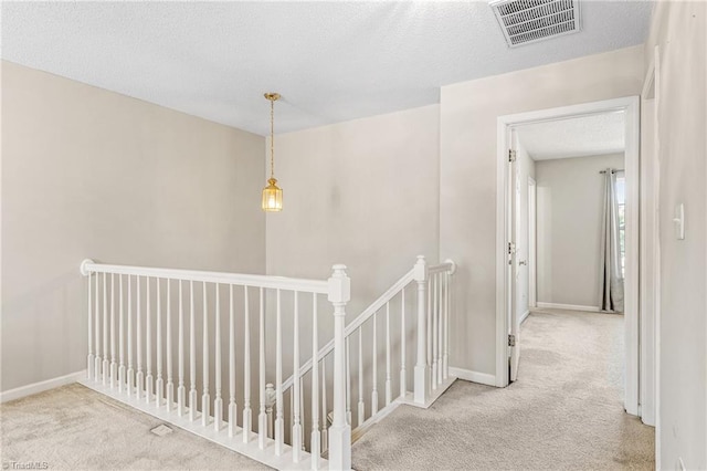 hall featuring a textured ceiling and light colored carpet