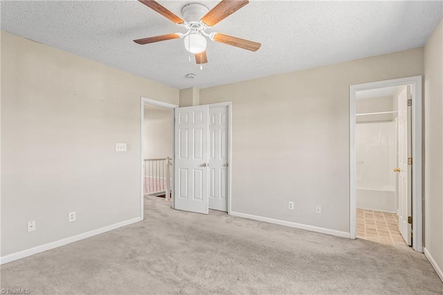 unfurnished bedroom featuring light carpet, a textured ceiling, connected bathroom, and ceiling fan