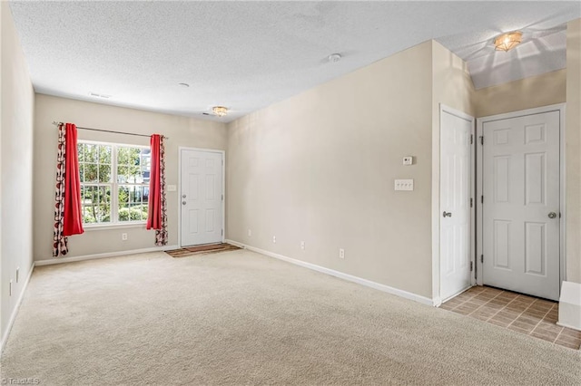 spare room with light colored carpet and a textured ceiling