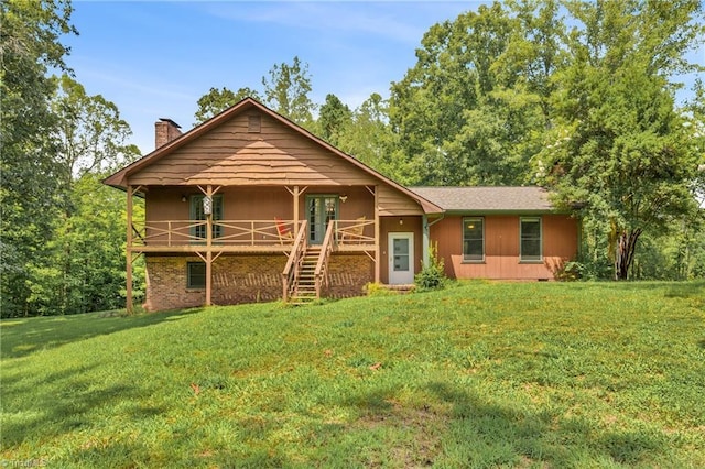 view of front of property with brick siding, a front lawn, a chimney, and stairway