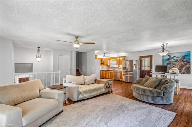 living room featuring a textured ceiling, ceiling fan, hardwood / wood-style floors, and sink