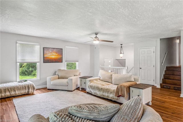 living room featuring hardwood / wood-style floors, ceiling fan, and a textured ceiling