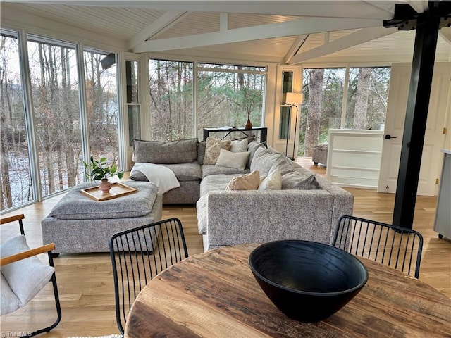 sunroom / solarium featuring ceiling fan, a wealth of natural light, and vaulted ceiling with beams