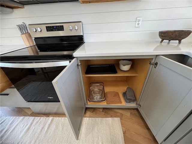 kitchen featuring electric stove, wood walls, and light wood-type flooring