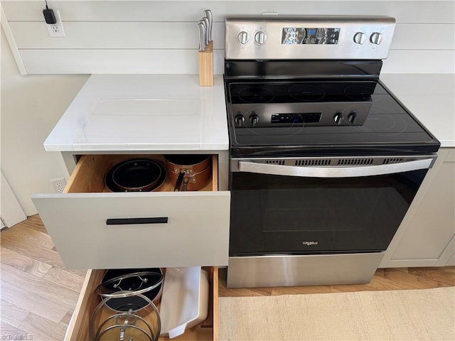 kitchen with white cabinetry, stainless steel electric range oven, and light wood-type flooring