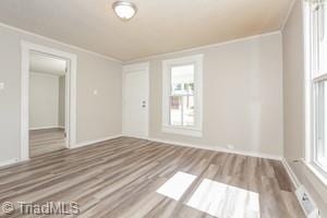 empty room with ornamental molding and light hardwood / wood-style floors