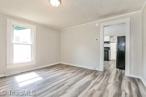 empty room with crown molding, hardwood / wood-style flooring, and a healthy amount of sunlight