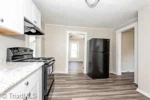 kitchen with black appliances, hardwood / wood-style flooring, ornamental molding, and white cabinets