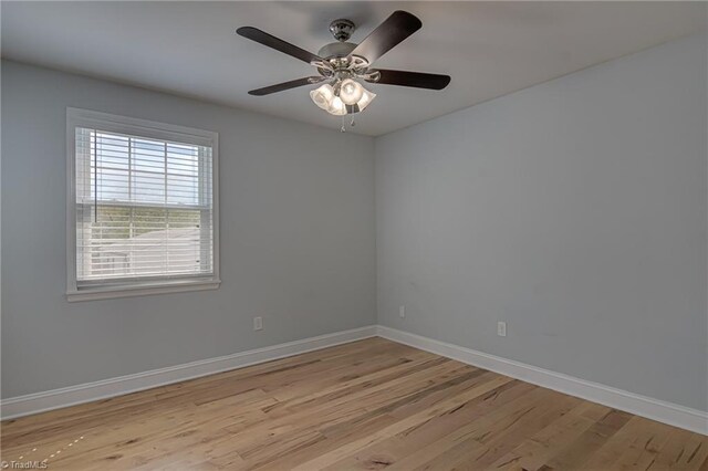 spare room featuring baseboards, light wood finished floors, and a ceiling fan