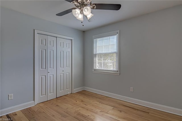 unfurnished bedroom featuring a closet, baseboards, light wood-type flooring, and ceiling fan