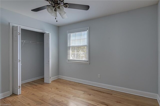 unfurnished bedroom with light wood-type flooring, a closet, baseboards, and a ceiling fan