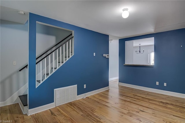 spare room featuring visible vents, baseboards, wood finished floors, and stairs