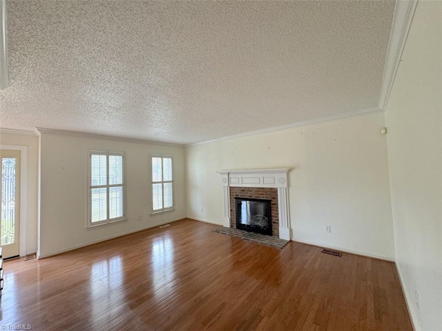 unfurnished living room featuring ornamental molding, a fireplace, a textured ceiling, and hardwood / wood-style flooring