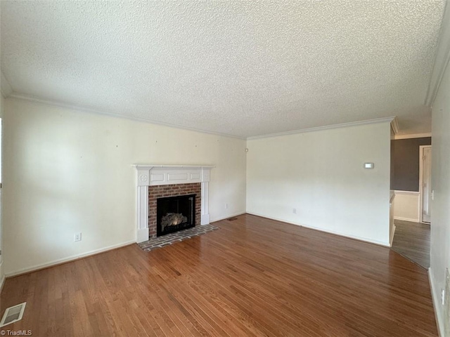 unfurnished living room featuring ornamental molding, hardwood / wood-style floors, a textured ceiling, and a brick fireplace