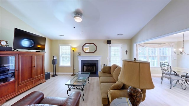 5423 Whitley Way, Greensboro, NC 27407 - living room featuring light wood-style floors, lofted ceiling, a chandelier, a fireplace with flush hearth, and a ceiling fan