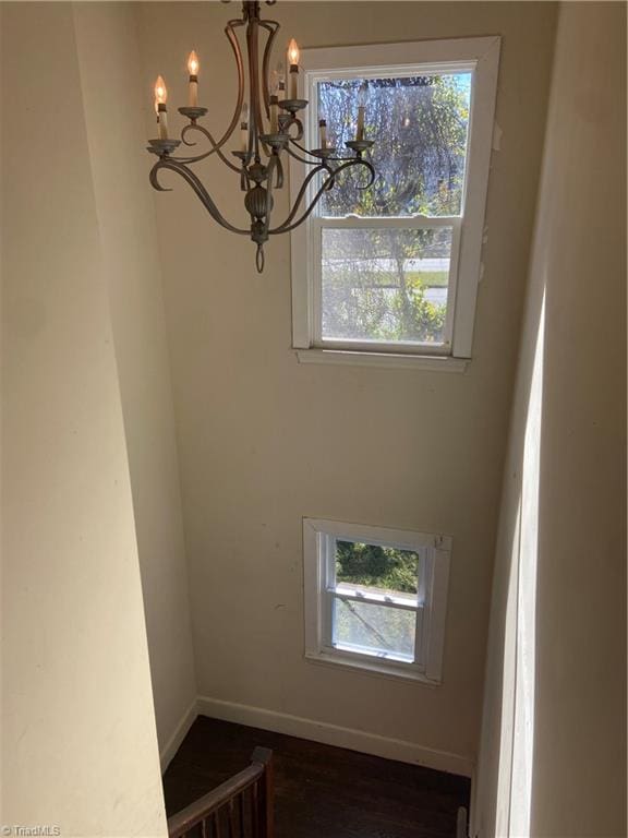 interior space with a wealth of natural light, dark wood-type flooring, and an inviting chandelier