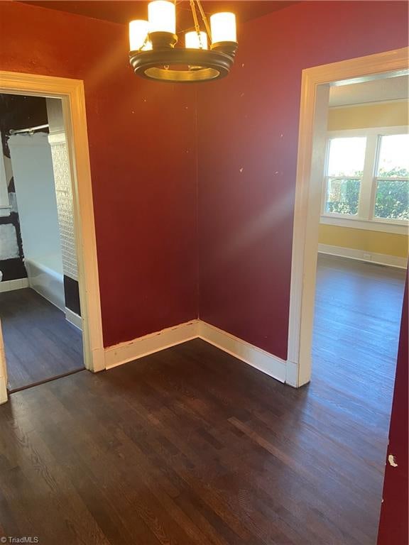 unfurnished dining area featuring dark hardwood / wood-style floors and an inviting chandelier