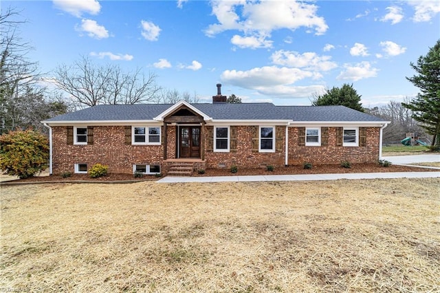 ranch-style home featuring brick siding, a chimney, and roof with shingles