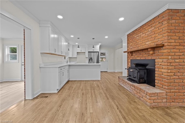 kitchen with crown molding, light wood-type flooring, light countertops, stainless steel fridge, and white cabinetry