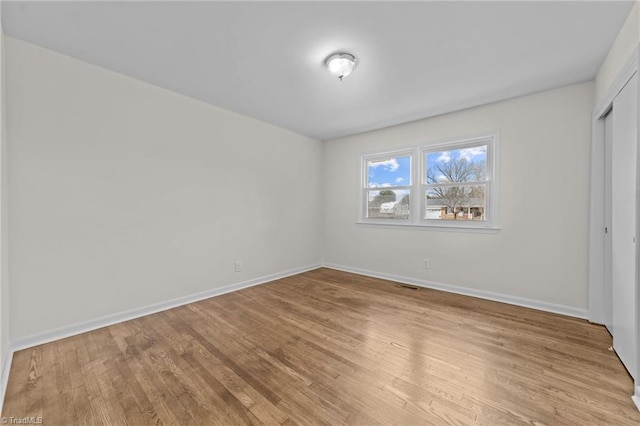 unfurnished bedroom with visible vents, light wood-style floors, baseboards, and a closet