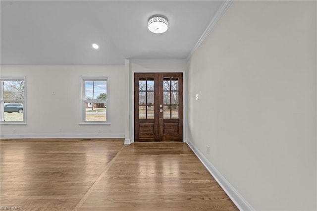 foyer entrance with crown molding, wood finished floors, baseboards, and french doors