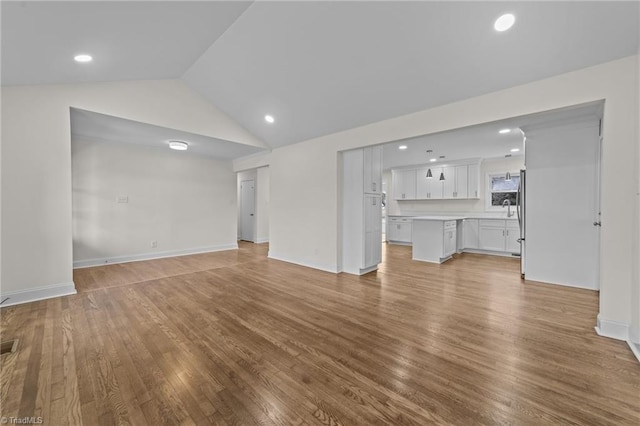 unfurnished living room with wood finished floors, baseboards, visible vents, recessed lighting, and vaulted ceiling