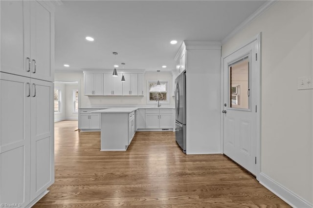 kitchen with wood finished floors, white cabinets, light countertops, and freestanding refrigerator