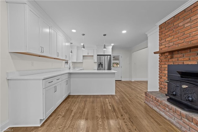 kitchen with a peninsula, white cabinets, stainless steel fridge with ice dispenser, light wood finished floors, and light countertops