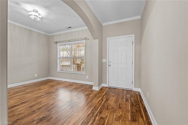 foyer with wood finished floors, baseboards, visible vents, arched walkways, and ornamental molding