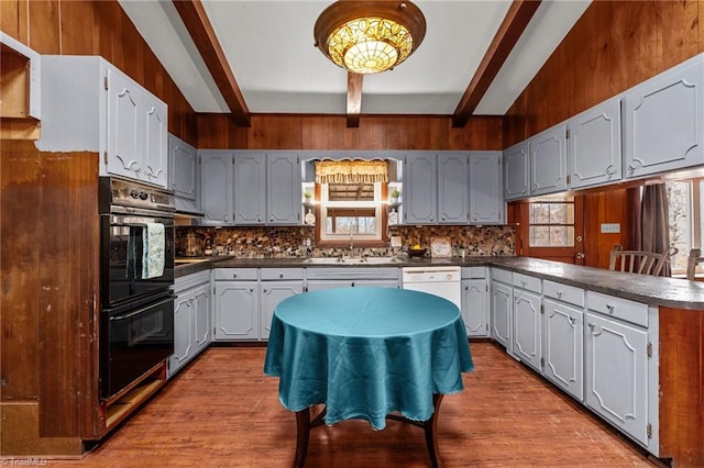 kitchen with beamed ceiling, wood walls, and light hardwood / wood-style floors