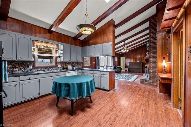 kitchen featuring wooden walls, sink, wood-type flooring, vaulted ceiling with beams, and gray cabinets