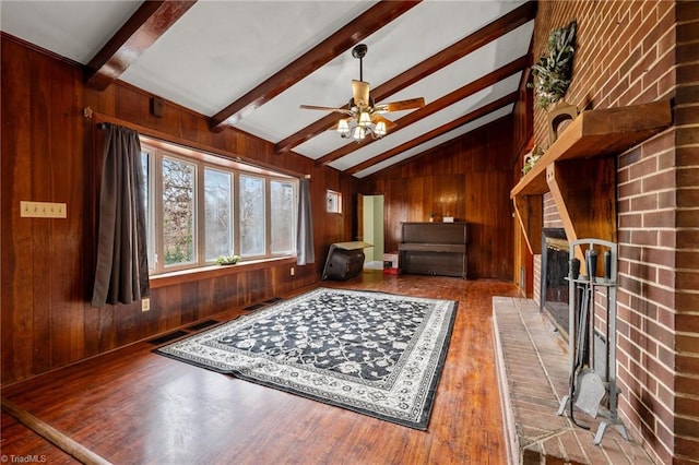 living room featuring vaulted ceiling with beams, wooden walls, ceiling fan, and wood-type flooring