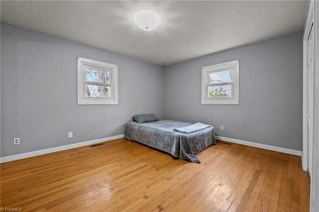 bedroom with light wood-type flooring and multiple windows