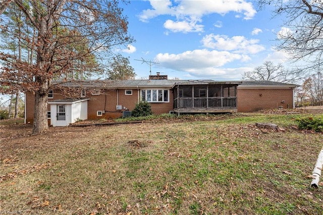 back of property with a lawn, a storage shed, and a sunroom