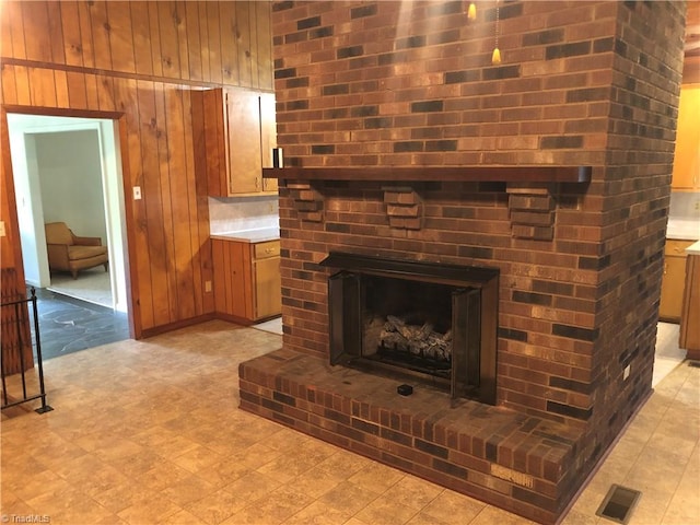 living room featuring a brick fireplace and wooden walls