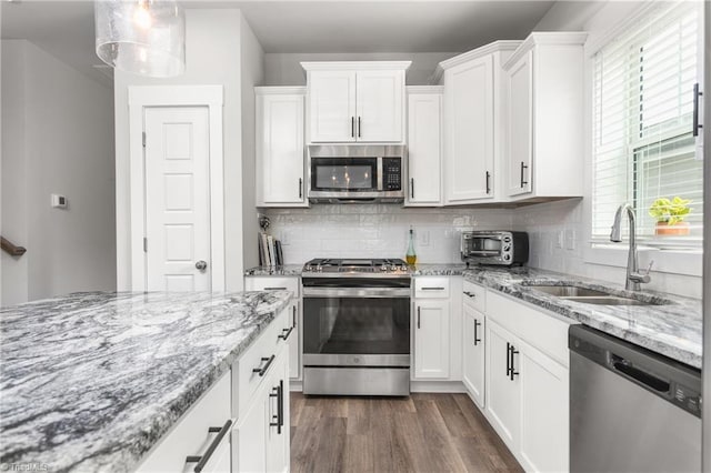 kitchen with sink, white cabinets, hanging light fixtures, stainless steel appliances, and dark wood-type flooring