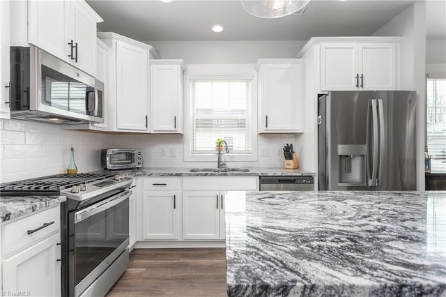 kitchen featuring dark hardwood / wood-style floors, white cabinetry, sink, stainless steel appliances, and light stone countertops