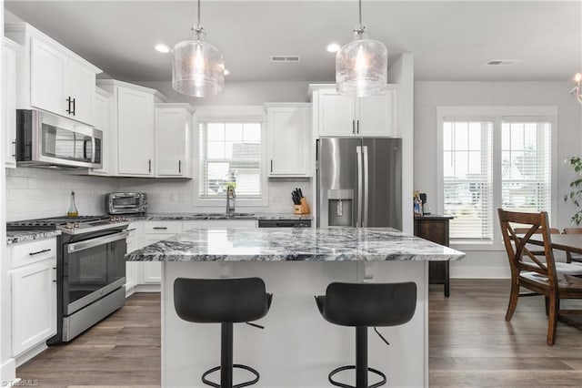 kitchen featuring white cabinetry, stainless steel appliances, a center island, and pendant lighting