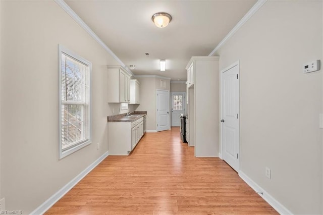 corridor featuring a sink, light wood-style flooring, baseboards, and ornamental molding