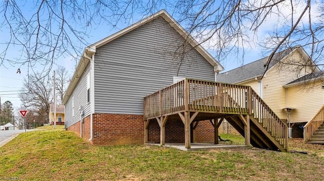 back of property with stairs, a yard, brick siding, and a wooden deck