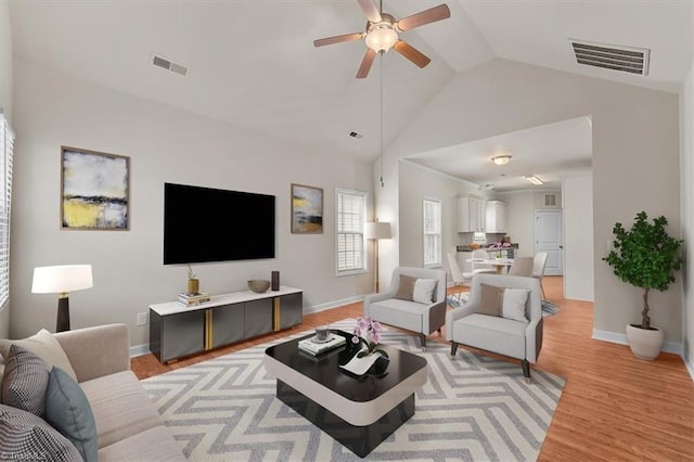 living area featuring vaulted ceiling, light wood-style floors, visible vents, and ceiling fan