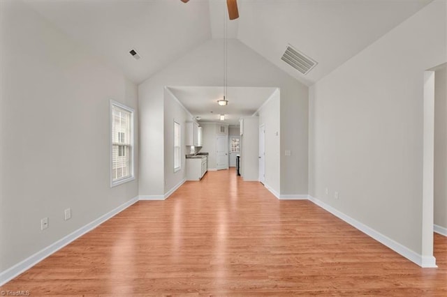 unfurnished living room featuring baseboards, visible vents, high vaulted ceiling, light wood finished floors, and ceiling fan