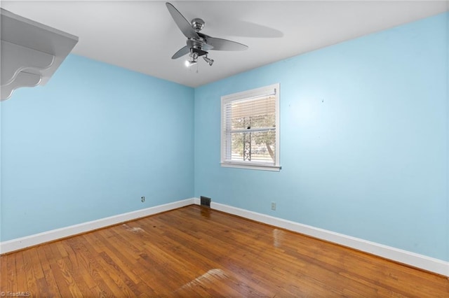 unfurnished room with a ceiling fan, wood finished floors, and baseboards