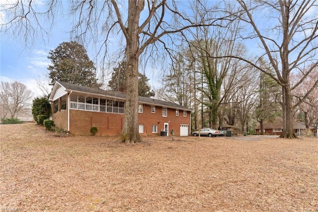 exterior space featuring an attached garage, brick siding, and a sunroom