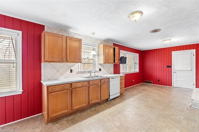 kitchen with visible vents, light countertops, brown cabinets, white dishwasher, and a sink