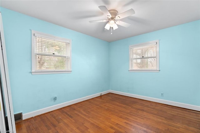 spare room featuring ceiling fan, visible vents, baseboards, and wood finished floors