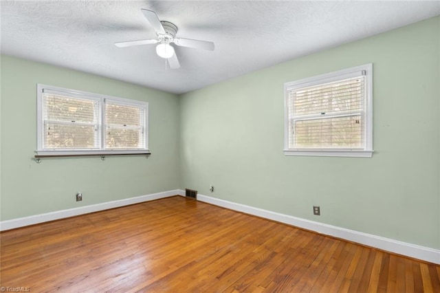 unfurnished room featuring visible vents, baseboards, ceiling fan, wood-type flooring, and a textured ceiling